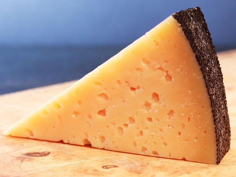 Gruyere Cheese Sliced on a Wooden Cutting Board