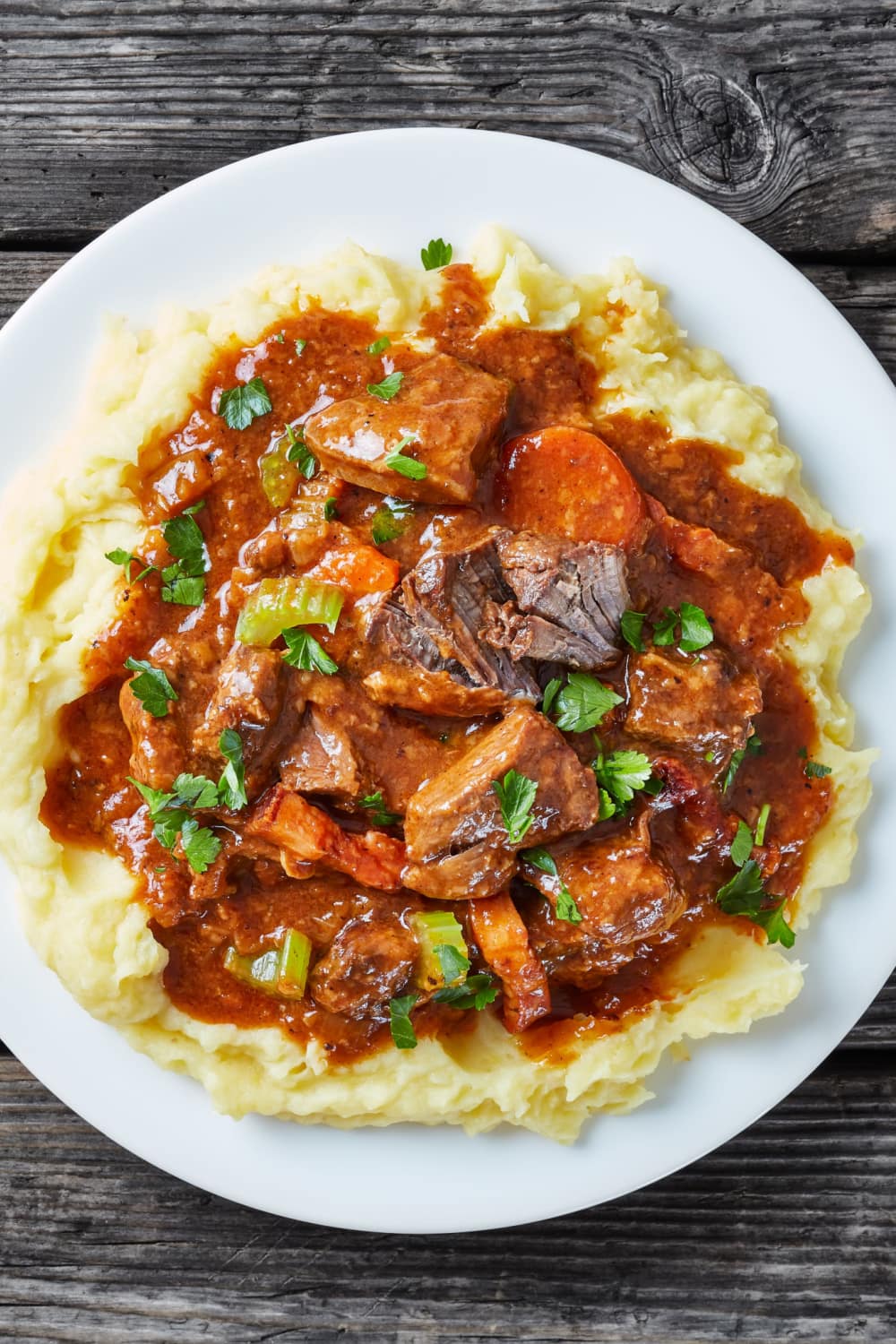 Guinness Beef Stew topped on mashed potato served on plate. 