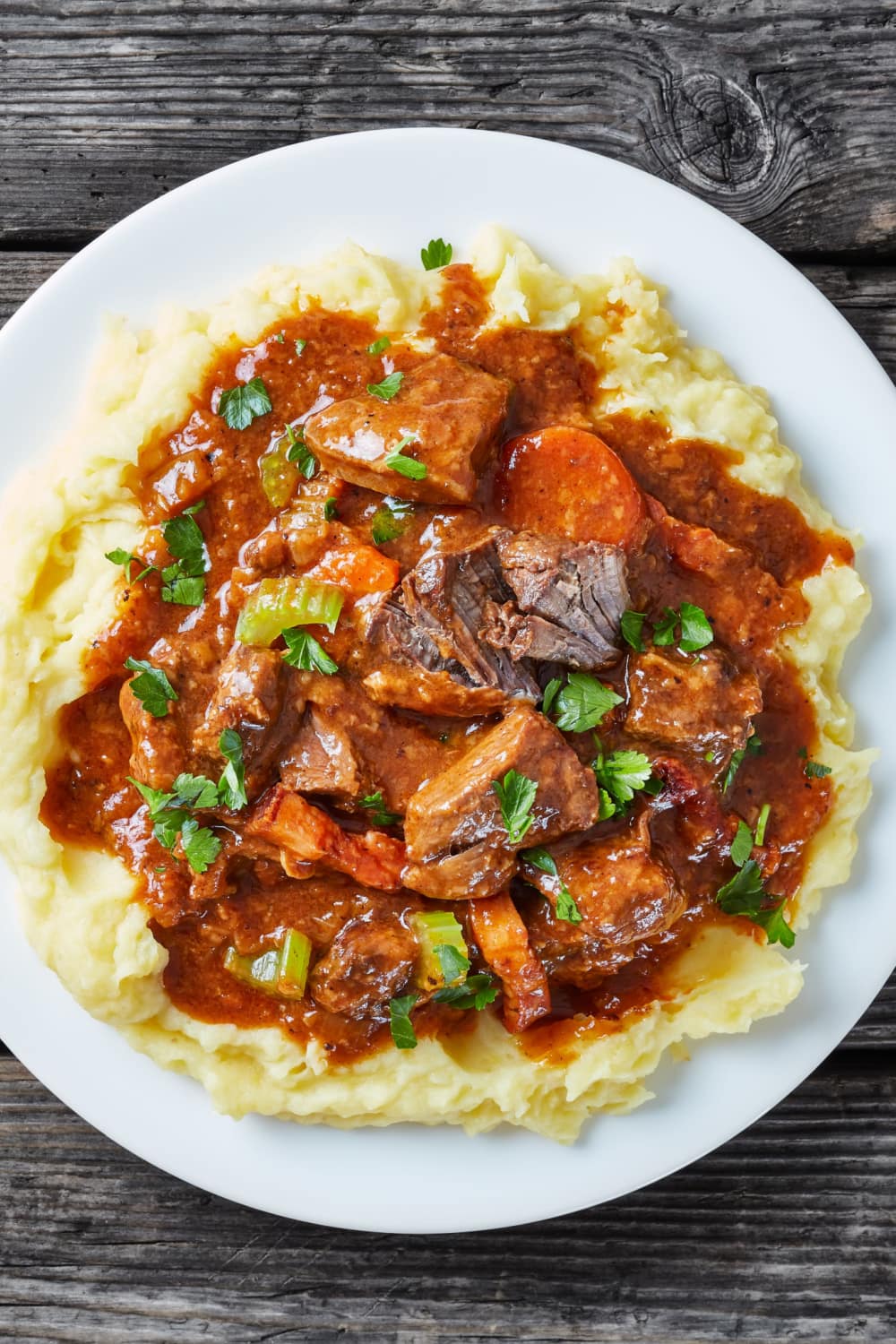 Guinness Beef Stew topped on mashed potato served on plate.