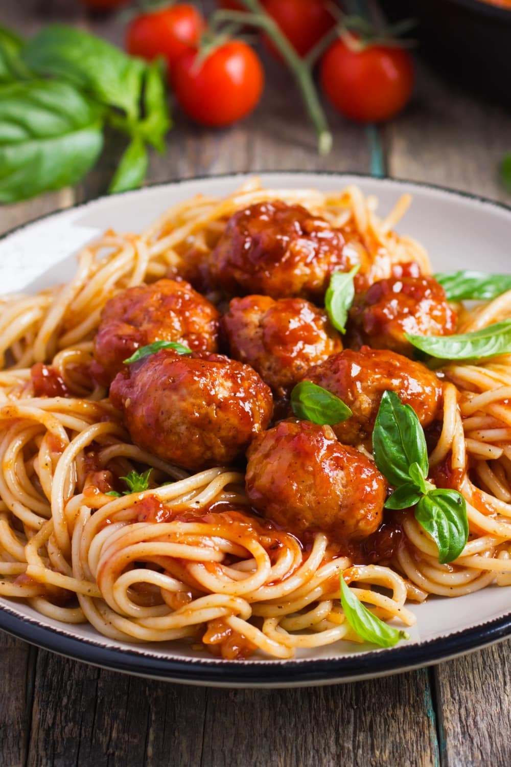 Saucy Spaghetti Topped With Meatballs Garnished With Fresh Basil Leaves