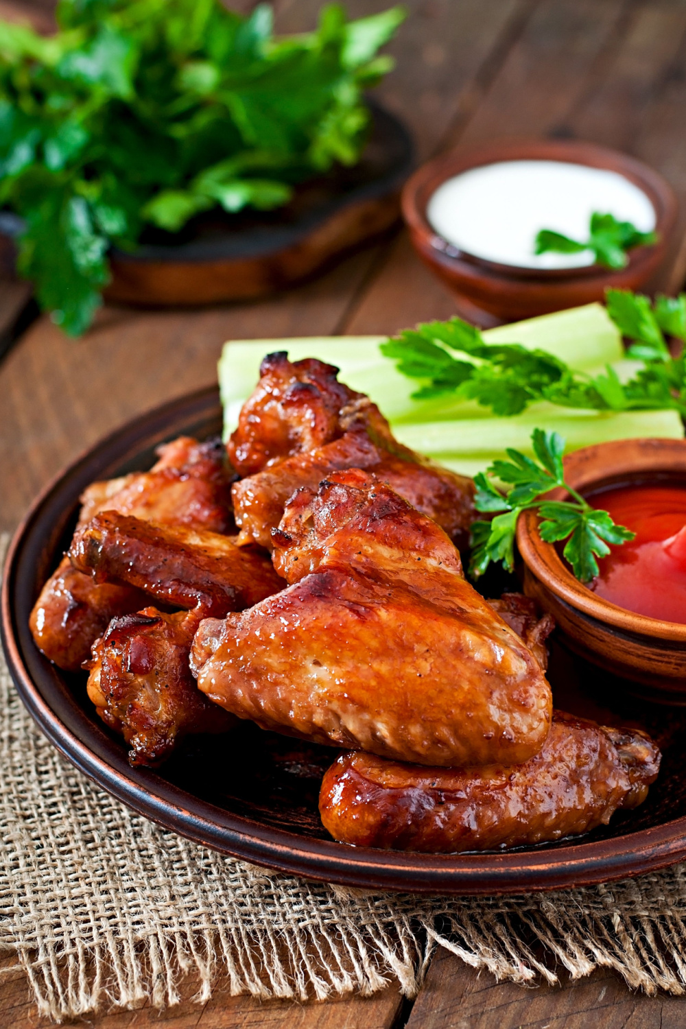 Chicken wings glazed in pineapple juice and soy sauce with celery stalks and ketchup served on a brown plate