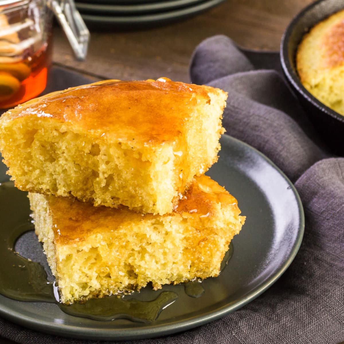 Sliced Corn Bread served on a black plate drizzled with honey