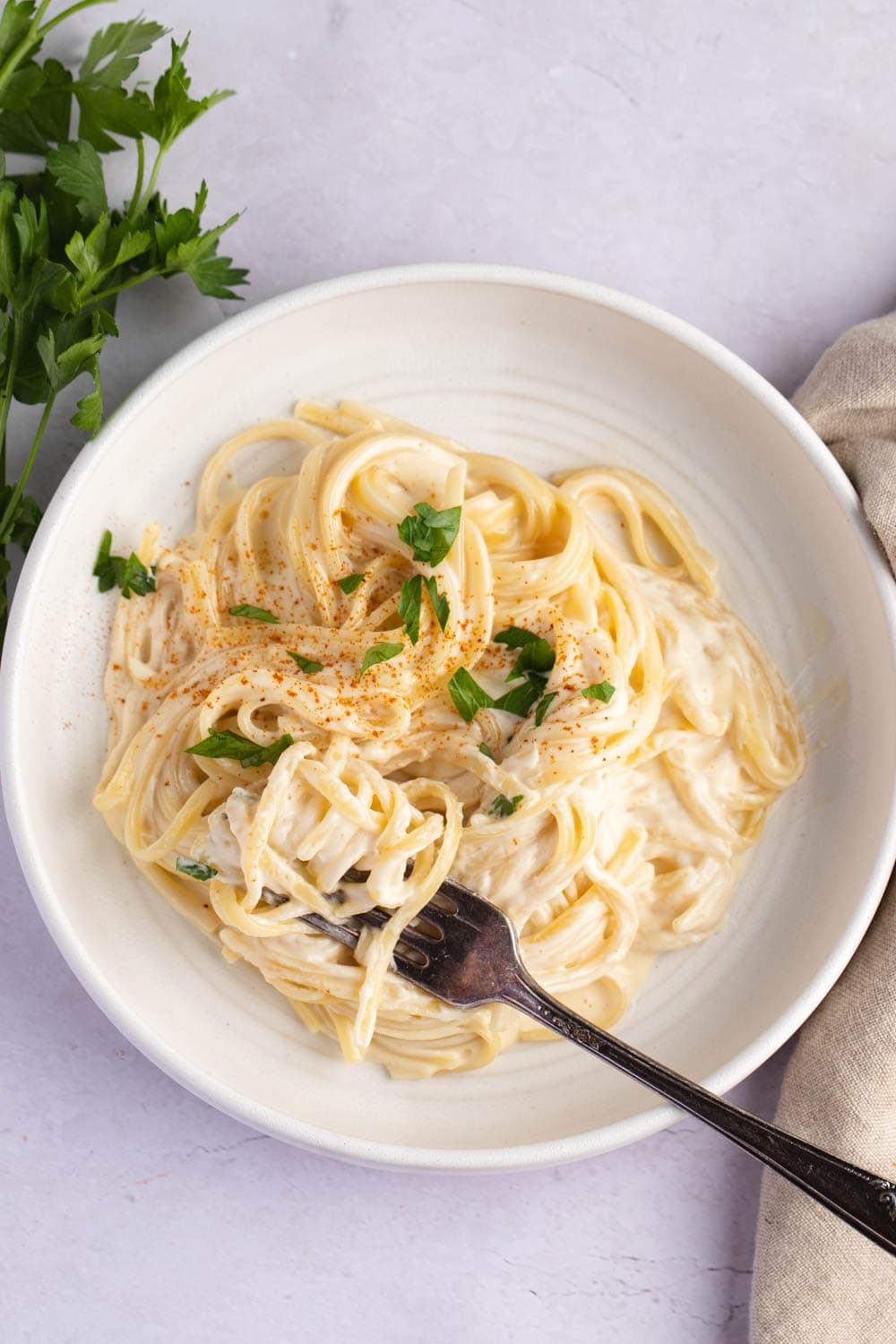 Creamy and Cheesy Noodles Romanoff Served on a White Plate, Garnished With Chopped Parsley Leaves, Sprinkled With Paprika