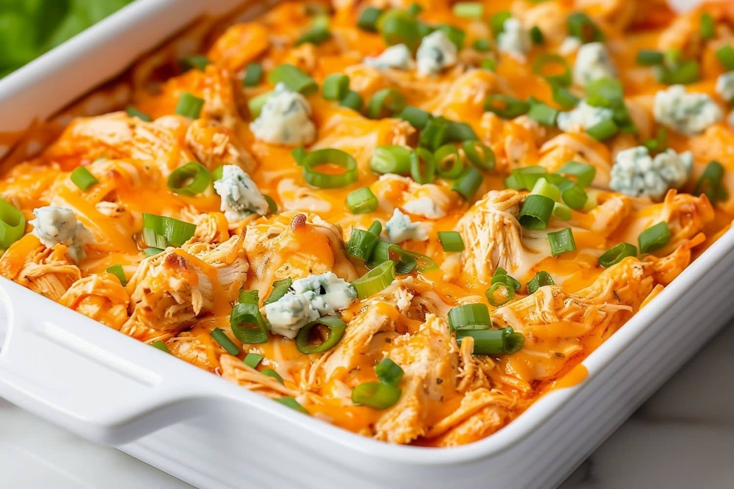 Frank's Buffalo Chicken Dip with Bleu Cheese and Green Onions in a White Casserole Dish