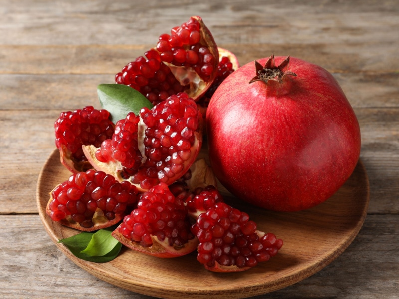 Sliced Open Ripe Pomegranates in a Wood Plate