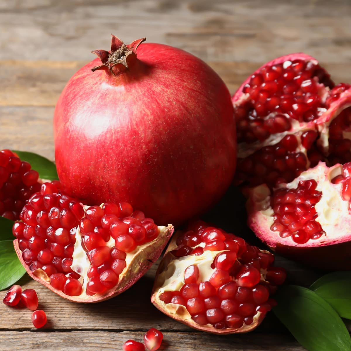 Ripe Whole and Cut Open Pomegranates on a Wooden Table