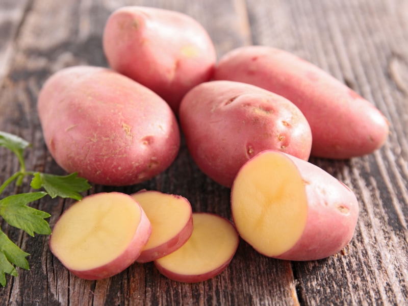 Whole and Slice Désirée Potatoes on a Wooden Table