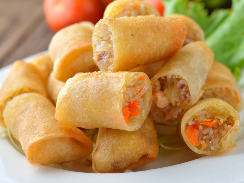 Cut in half fried spring rolls served on a white plate
