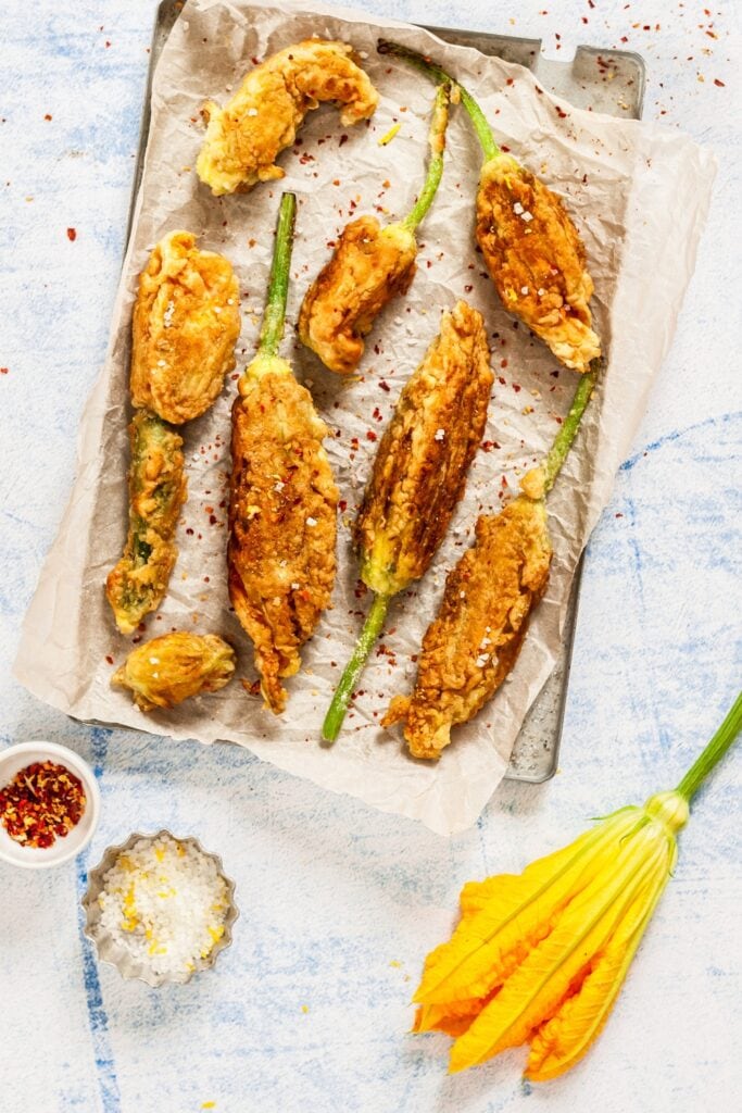 Fried, Breaded Squash Blossom on a Baking  Sheet With Parchment Paper Sprinkled With Chili Peppers and Salt
