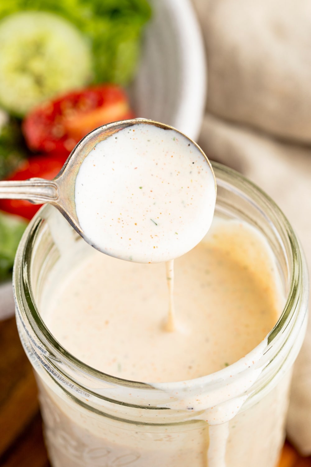 Ranch Dressing Sauce in a Jar Dripping from a Spoon, A Bowl of Salad in the  Background