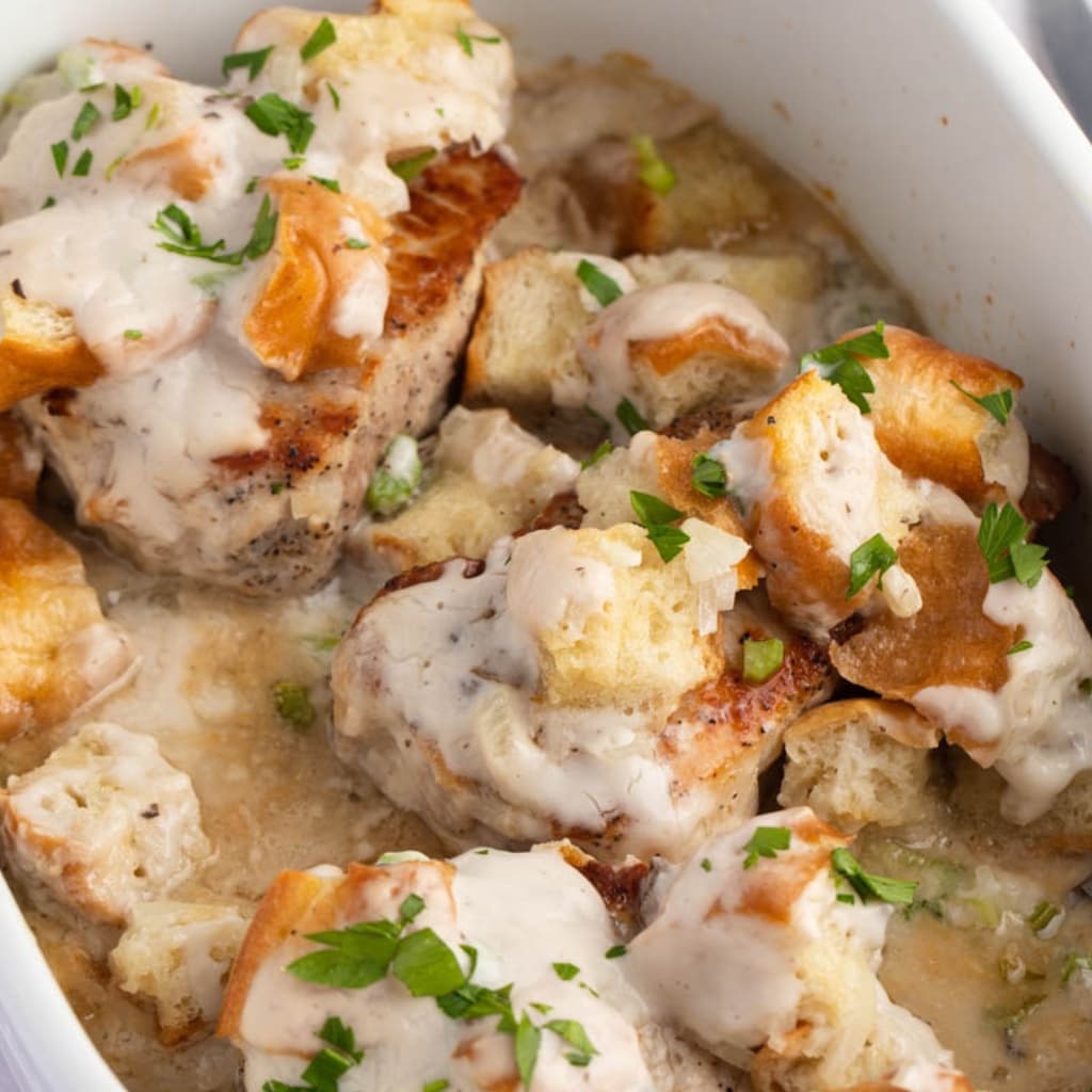 Closeup of Baked Stuffed Pork Chops with Celery and Onions on a White Casserole Dish