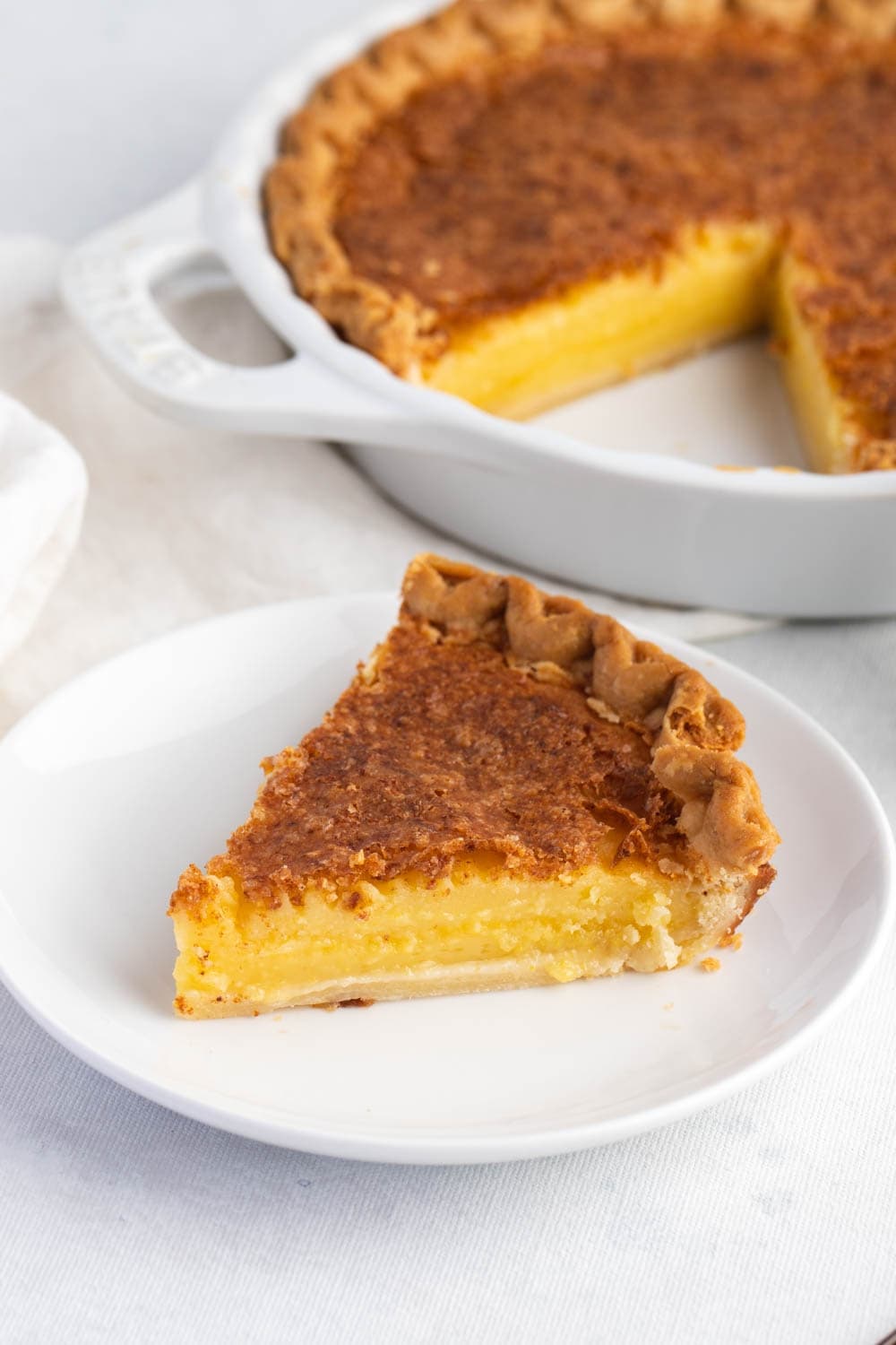 A serving of chess pie with creamy custard filling and crumbly toppings on a white plate.