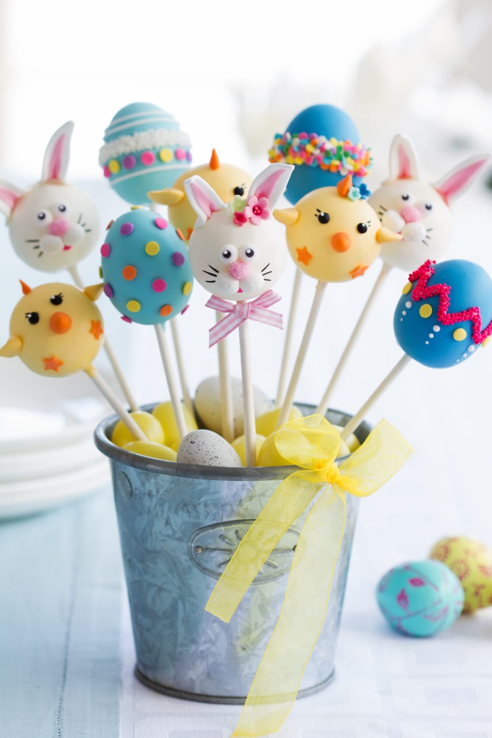 Easter Cake Pops of Bunnies and Easters Eggs, Standing on a Small Blue Filled With Easter Egg Candies