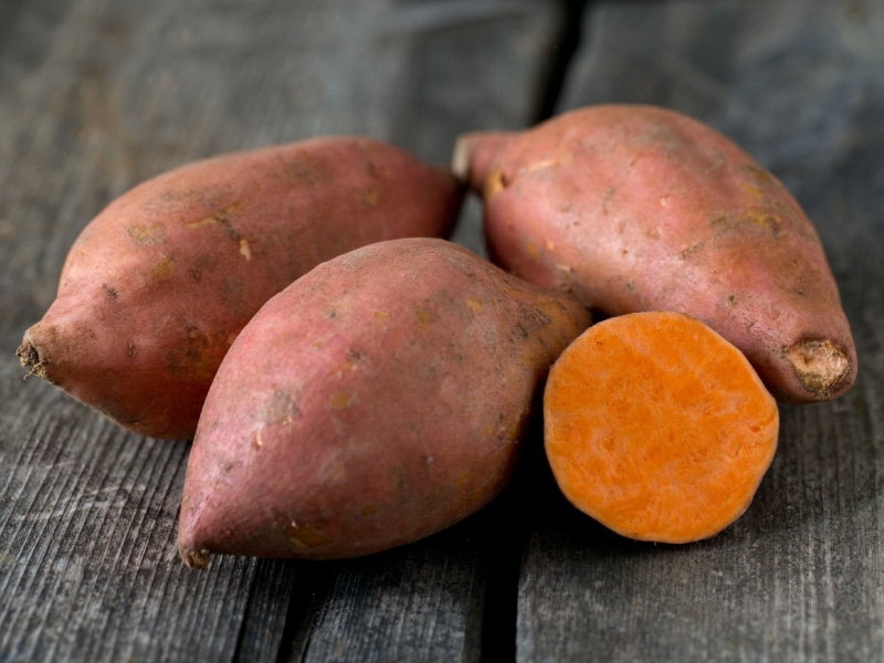 Raw Sweet Potatoes on Top of a Wooden Table