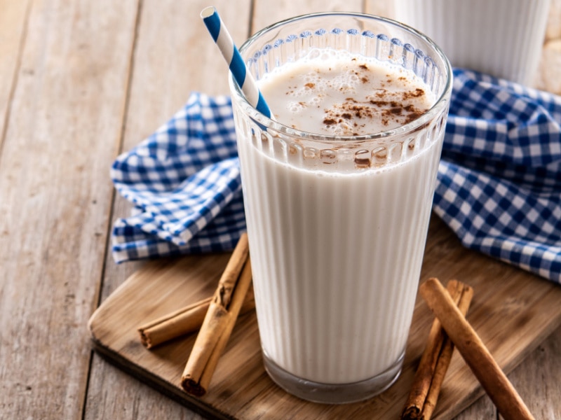 A Glass of Horchata on a Wooden Table With Cinnamon Sticks Beside