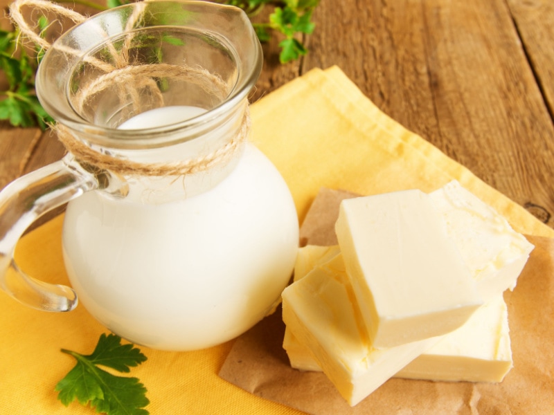 A pitcher of milk and sliced blocks of butter. 