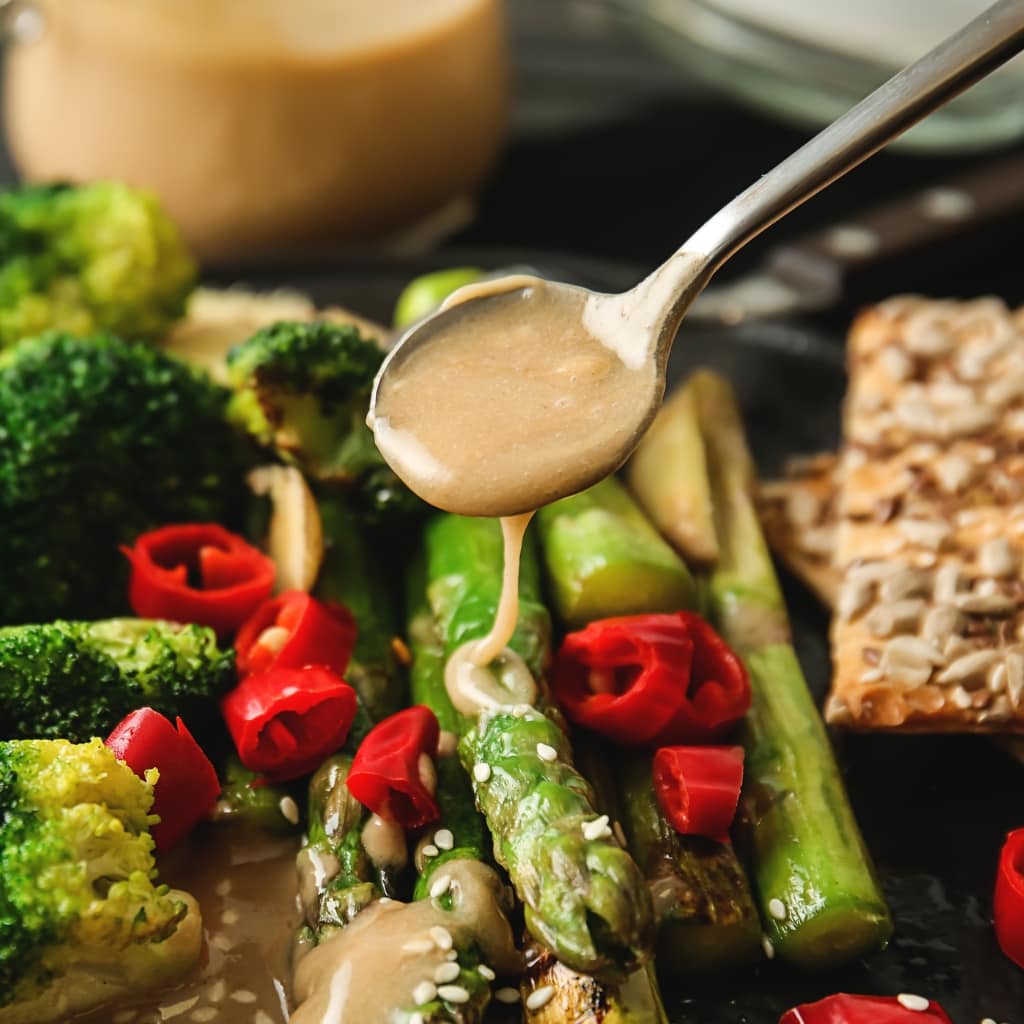 Fresh Asparagus and Broccoli Pan Seared, Garnished With Sliced Chili and Sesame Seeds, Drizzled With Tasty Tahini Sauce