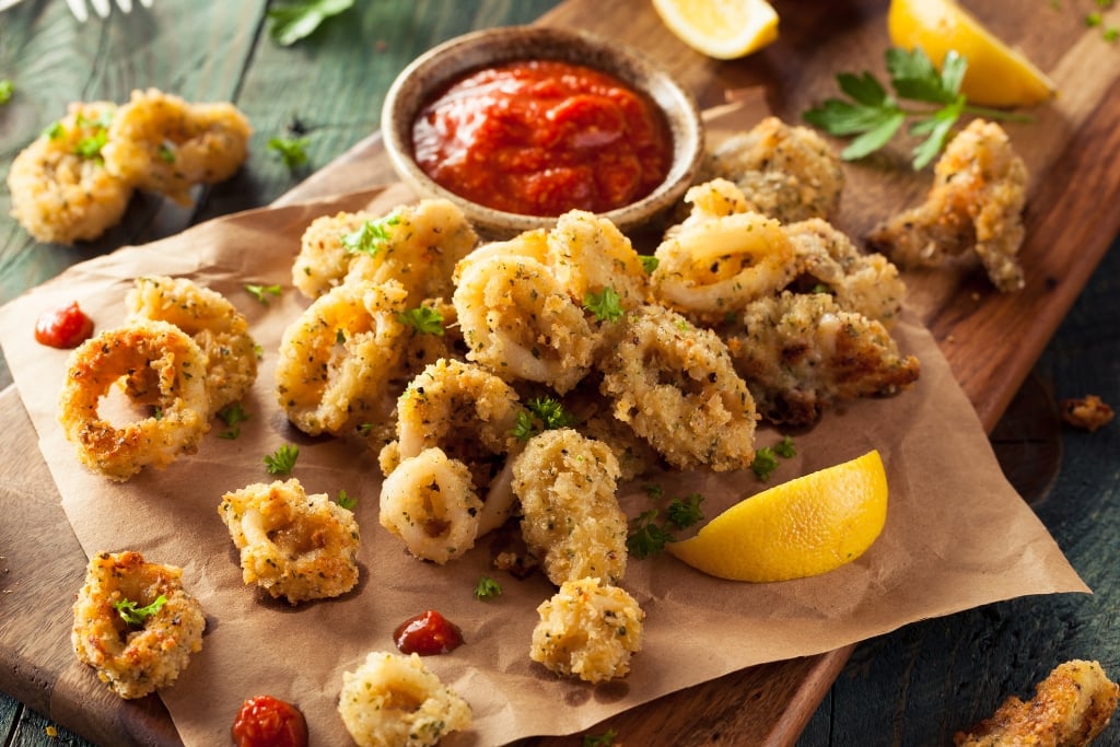 Crispy Calamari Rings Served With Homemade Ketchup On A Wooden Board.