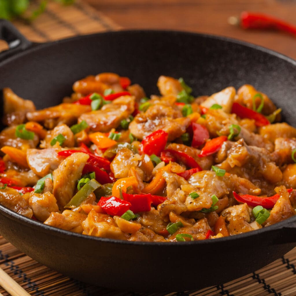 Kung Pao Chicken in a Wok Made With Chicken Meat, Red Bell Pepper and Onion