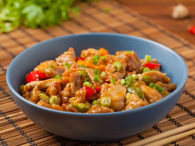 Kung Pao Chicken in a Bowl Garnished Chopped Onion Leaves