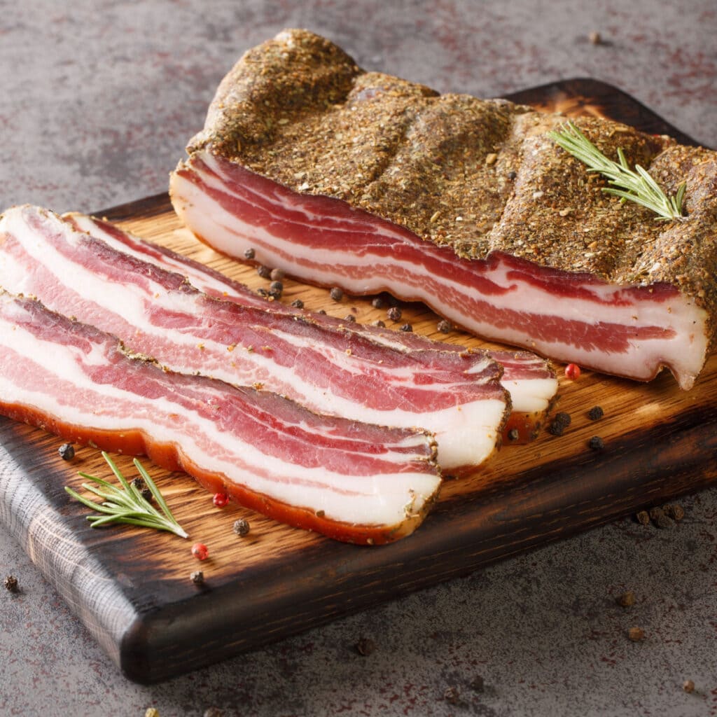 Cured Pancetta with Salt and Pepper on a Wooden Cutting Board