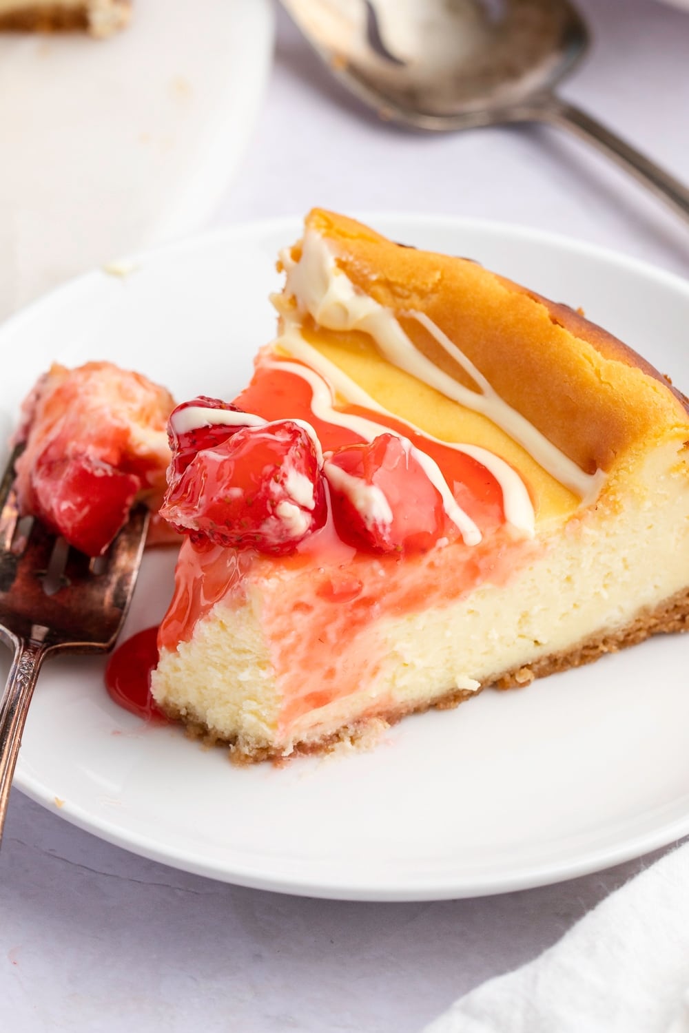 A Slice of White Chocolate Cheesecake with Strawberry Sauce Served on a White Plate