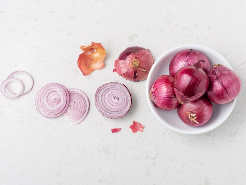 Overhead view of shallots with sliced onions in a white bowl