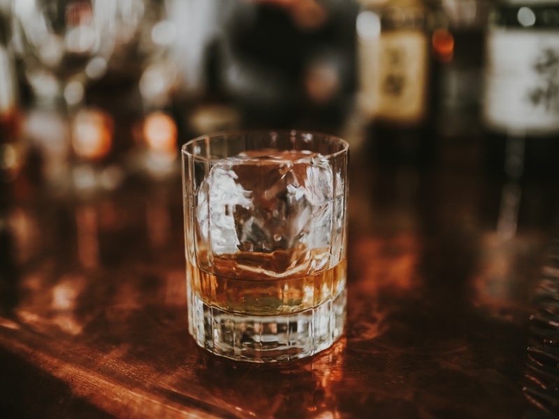 Glass of Japanese Whisky With a Cube of Ice on the Bar Station