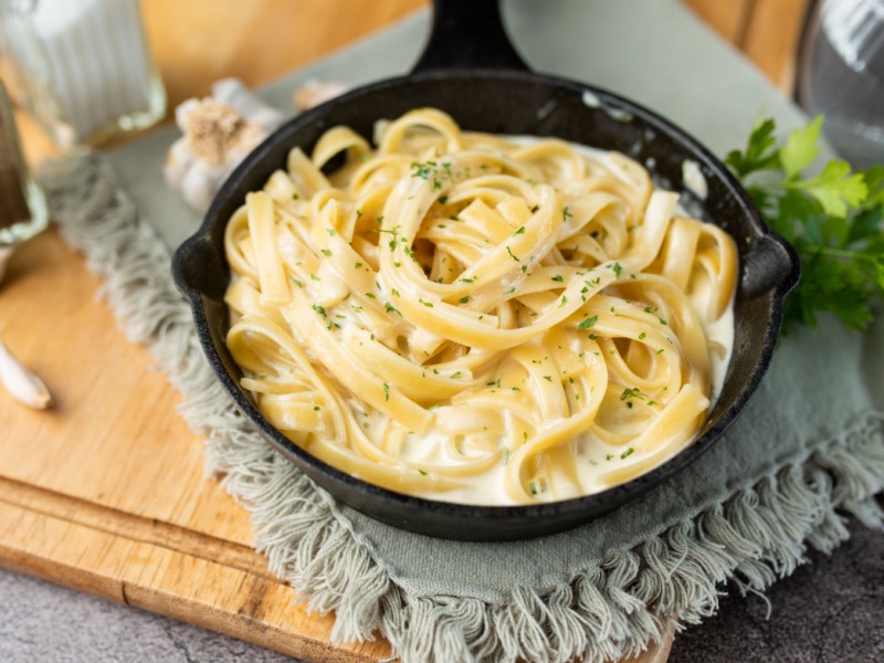 Pasta with Alfredo Sauce in A Skillet on a Cutting Board