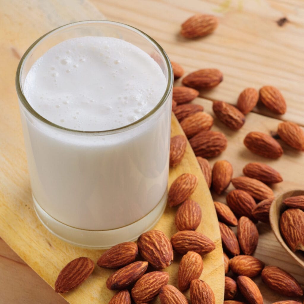 A Glass of Almond Milk and Almond Nuts in a Wooden Table