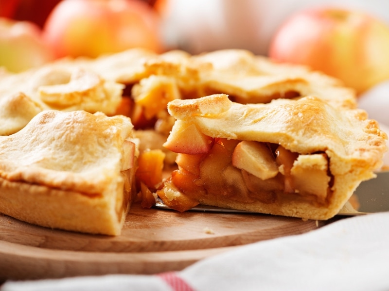 Thick Apple Pie on a Wooden Cake Stand, a Slice of Pie Pulled Out