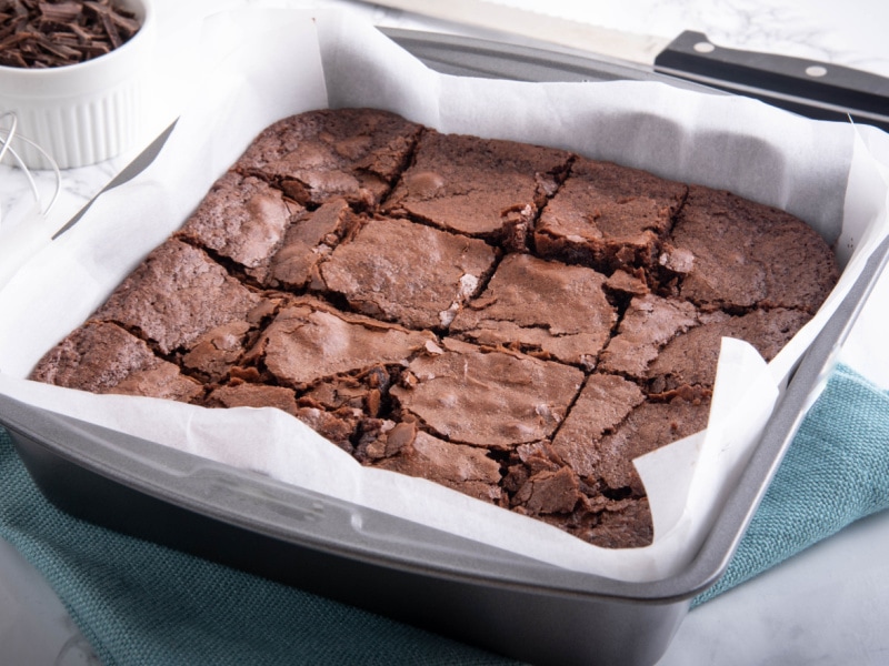 Sliced Brownie on a Pan With Baking Sheet Layer on Top of a Blue Green Cloth