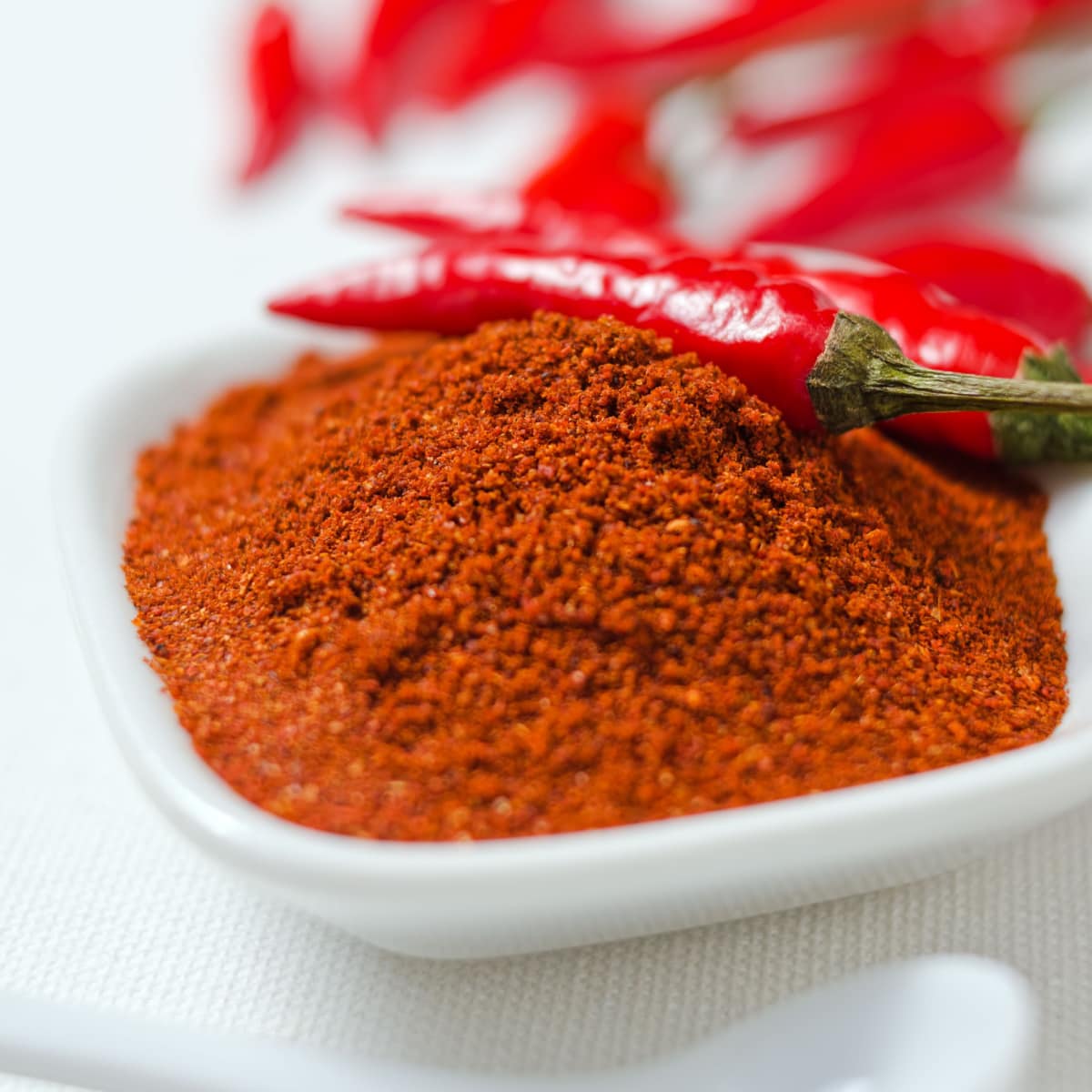 Cayenne Pepper Powder on a Side Dish with Raw Cayenne Pepper