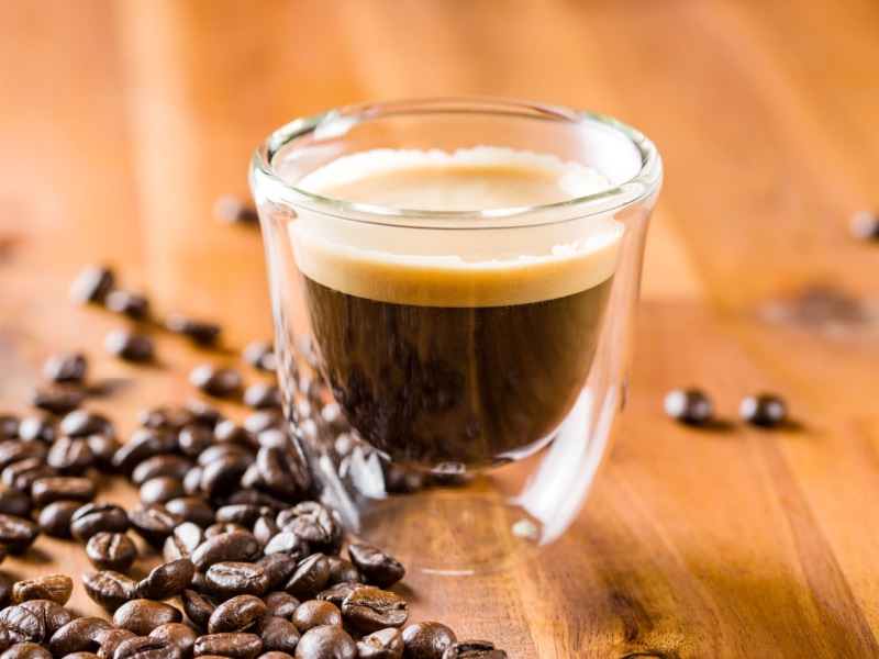 A Glass of Espresso and Coffee Beans on a Table