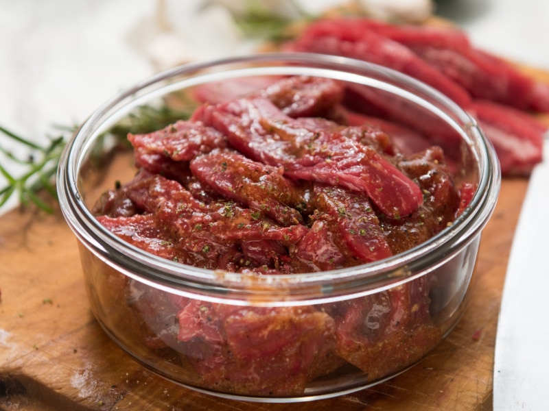 Slices of Flank Steak Marinated on a Clear Bowl