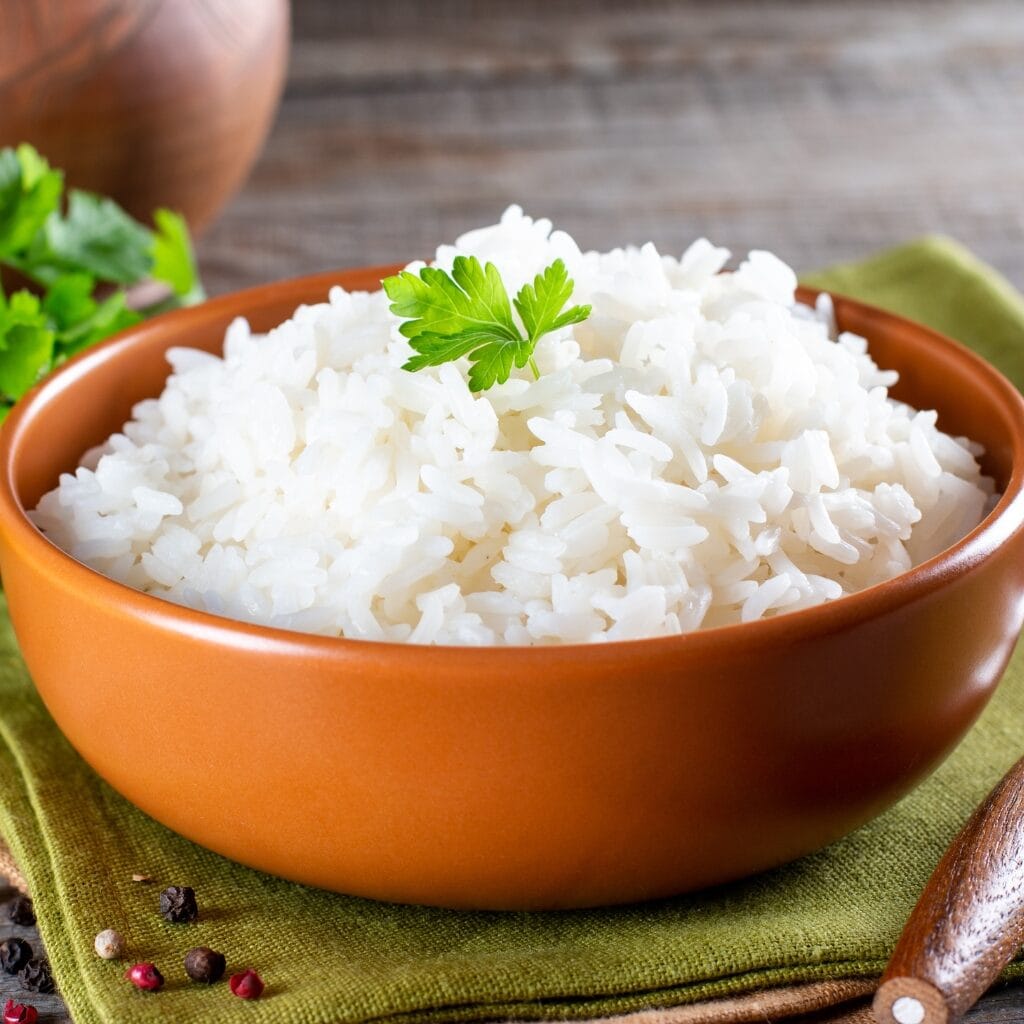 Homemade Cooked White Rice in a Brown Bowl with parsley leaf on top