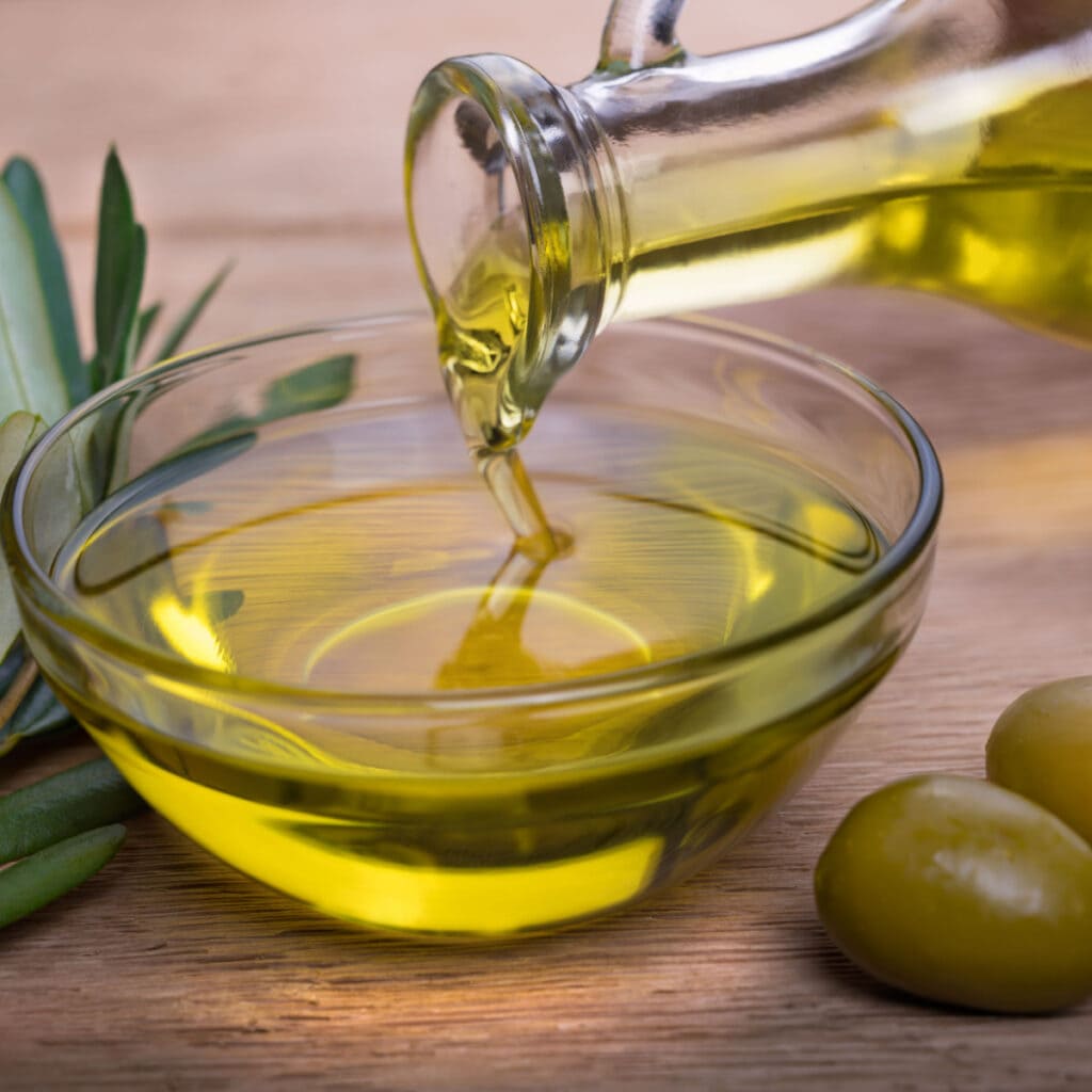 A Bowl of Olive Oil and Olives on a Wooden Table