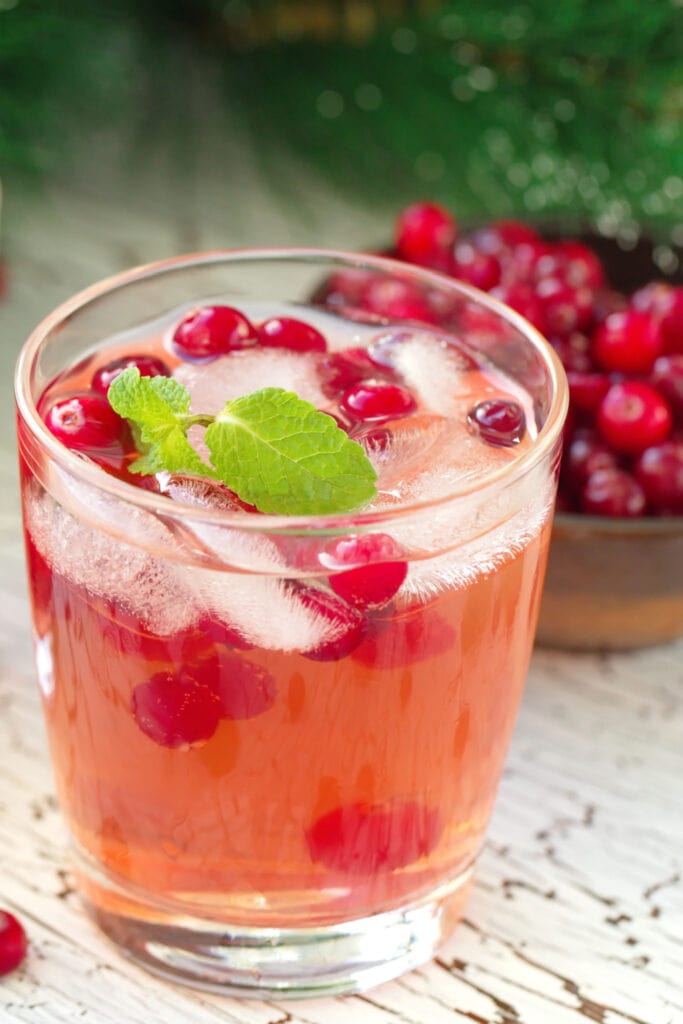 A Glass of Pink Whitney and Cranberry Juice and Cranberries in Background