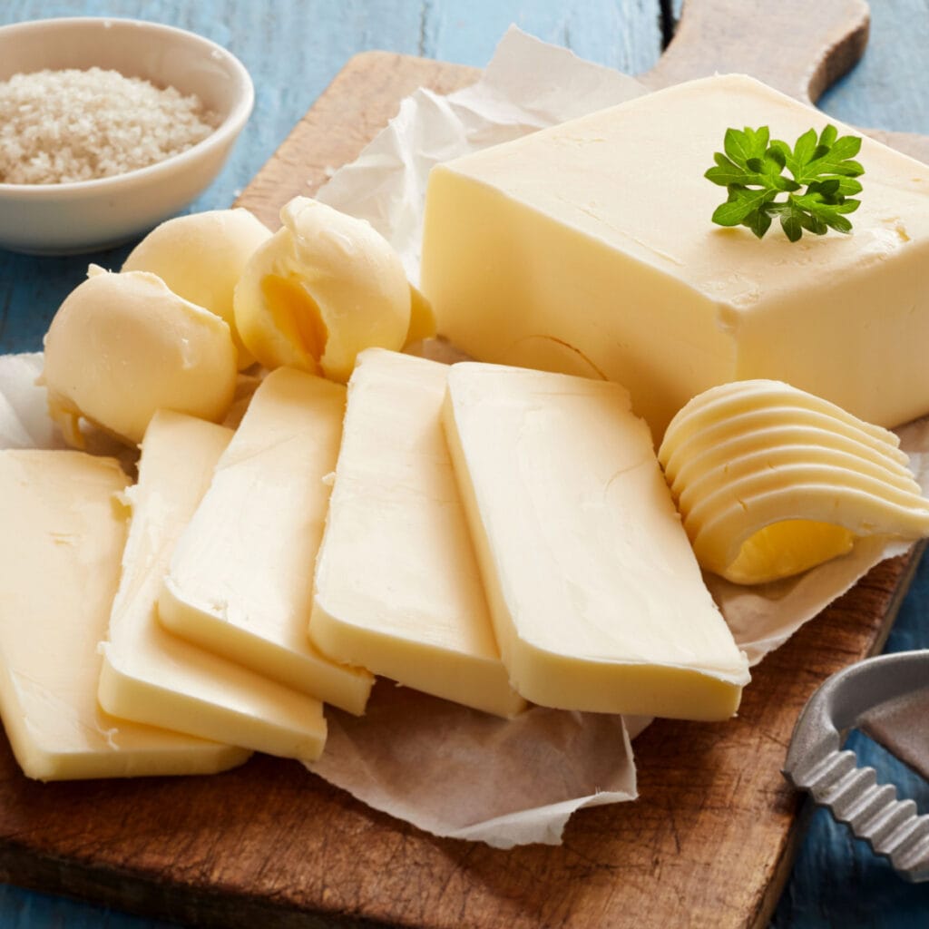 Whole and Sliced Butter on a Wooden Cutting Board