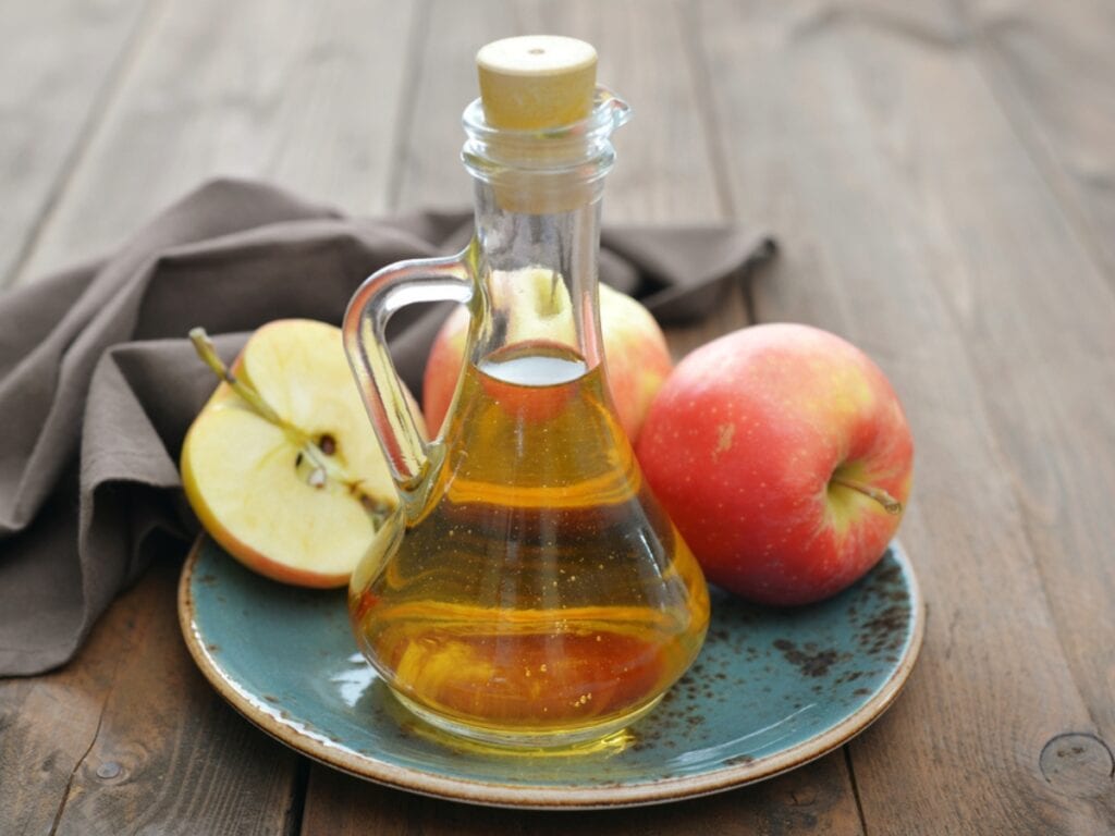 Apple Cider Vinegar In Glass Bottle And Fresh Apples On Wooden Background