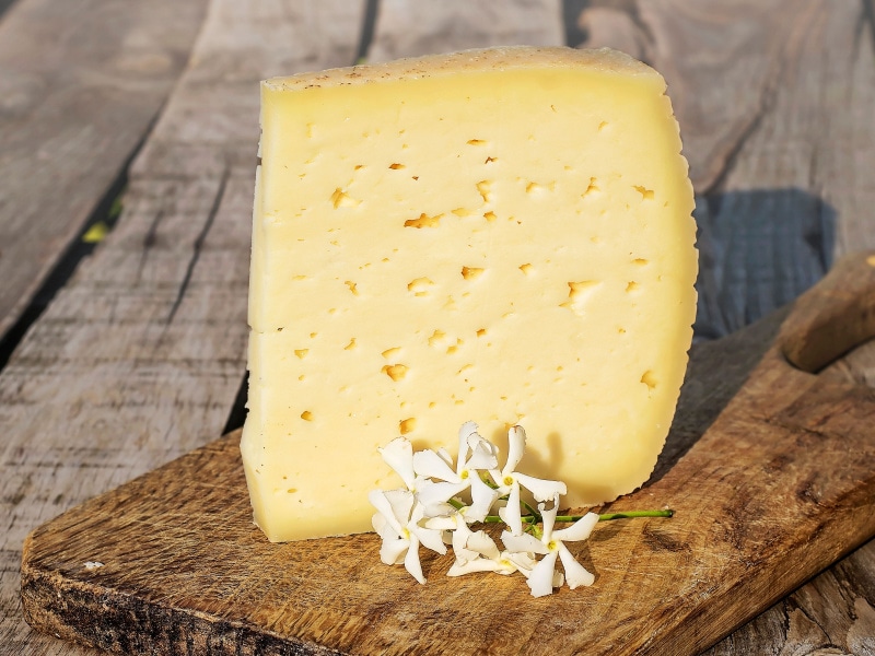 Sliced Block of Asiago Cheese on a Wooden Cutting Board