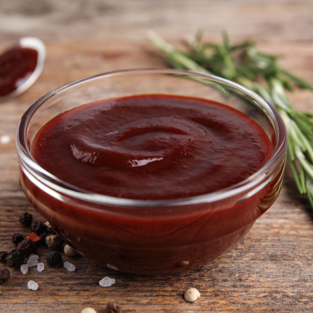 A Bowl of Barbecue Sauce with Herbs and Spices on a Wooden Table