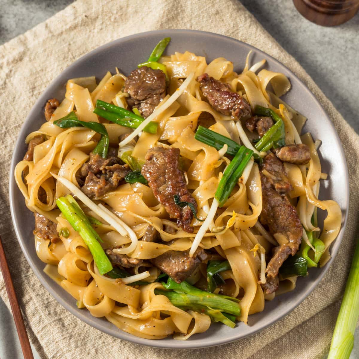 Chow Fun vs. Mei Fun- All You Need to Know featuring Stir Fry Beef Chow Fun on a Plate with Lemongrass