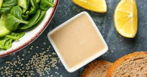 Bowl of Tasty Tahini with Sesame Seeds, Lemon, Bread and Spinach