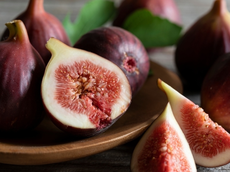 Whole and Sliced Brown Turkey Figs Served on a Wooden Plate