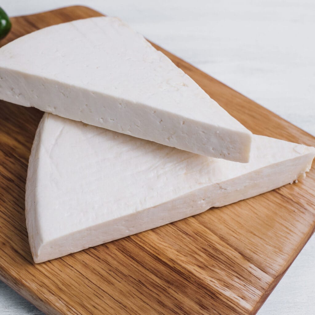 Slices of Cojita Cheese on a Wooden Cutting Board