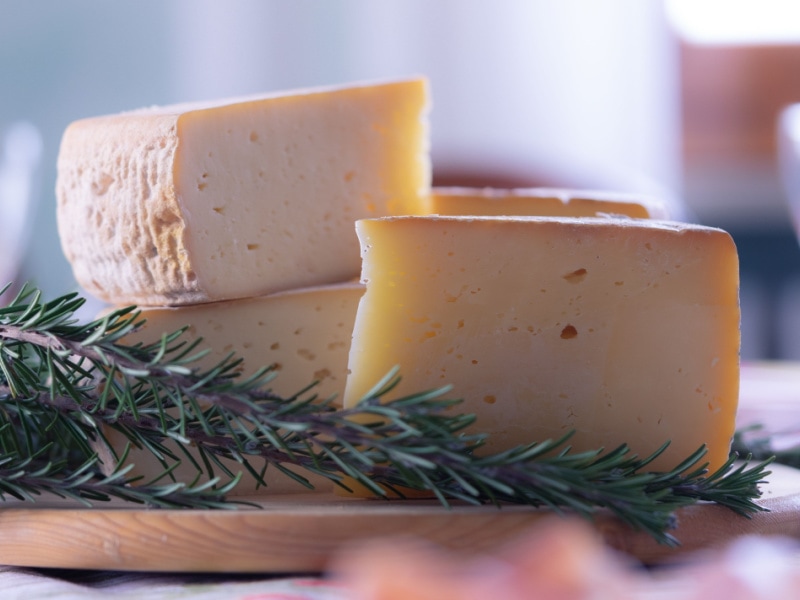 Slices of Fontina Cheese and Thyme on a Wooden Cutting Board