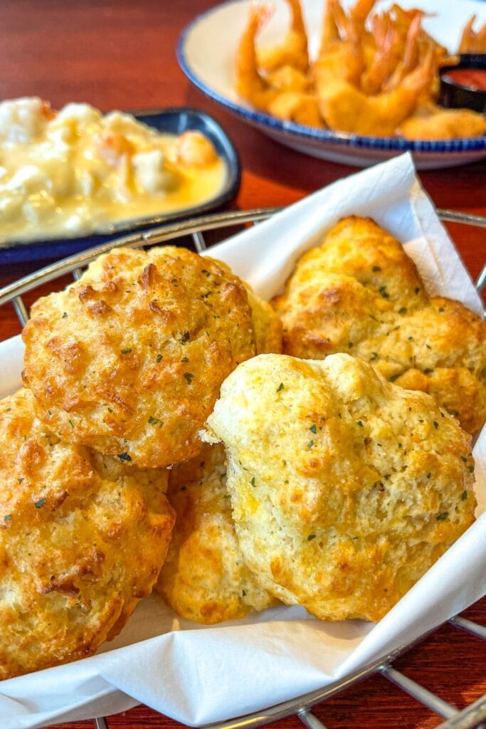 5 Homemade Cheddar Bay Biscuits in a Bread Basket with Lobster Ravioli and Shrimp in the Background