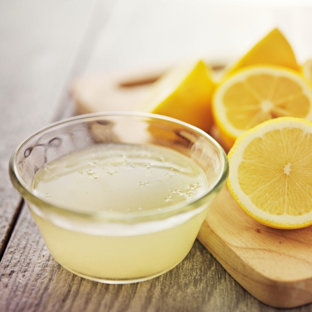 Lemon Juice in a Small Bowl Next to Cutting Board with Slices of Fresh Lemons