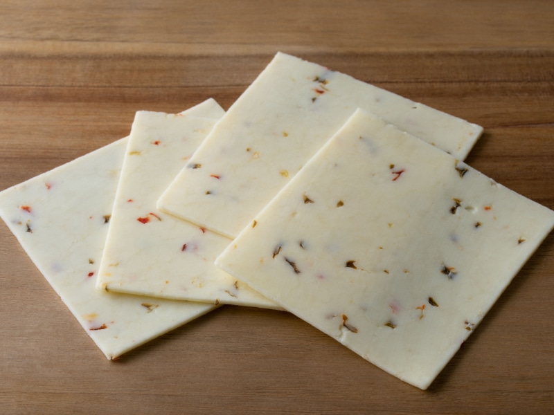 Four Slices of Monterey Jack Cheese on a Wooden Table